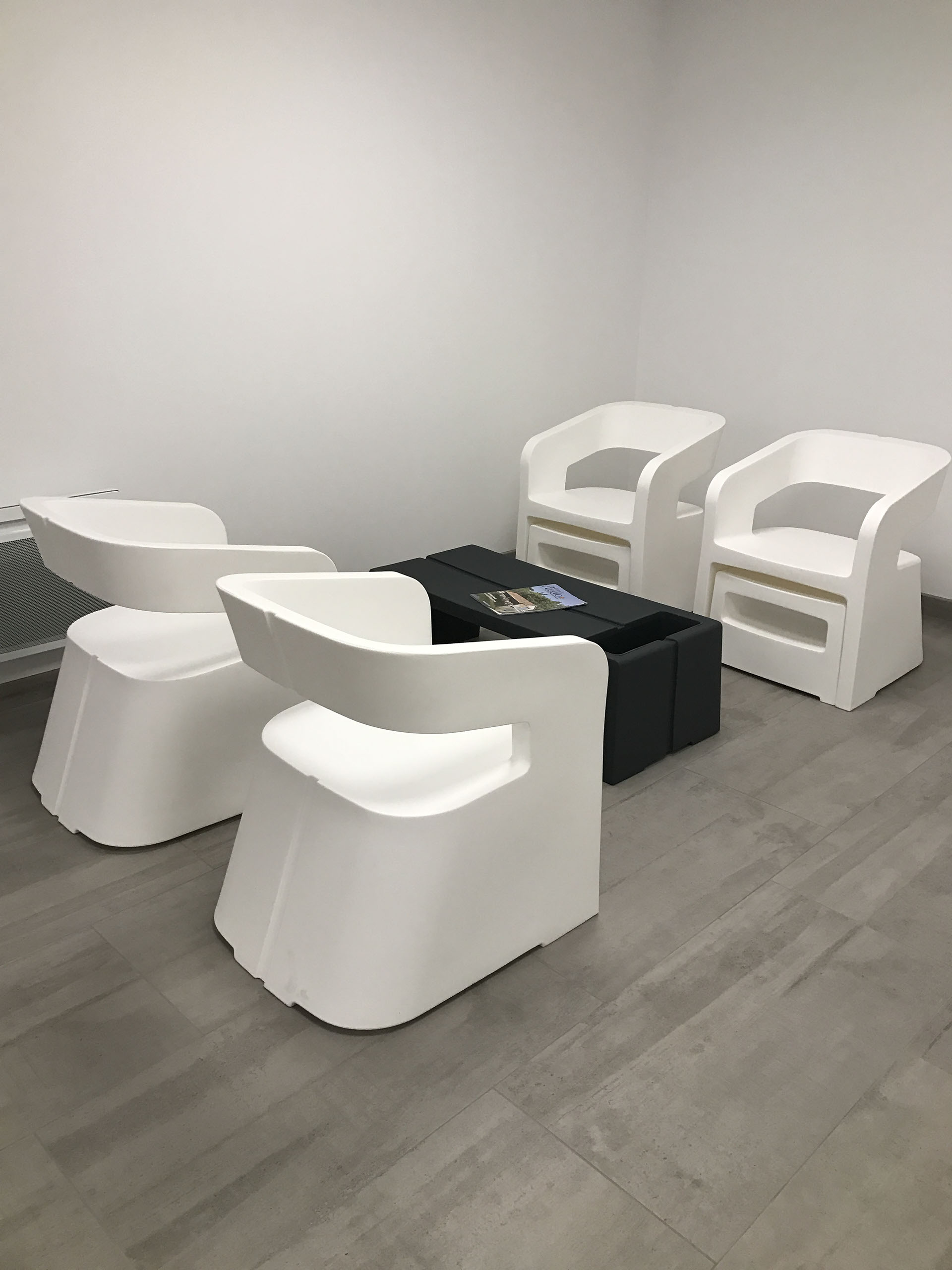 photo d'une réalisation, d'un espace d'attente avec table basse noire et fauteuils blanc, de l'entreprise Riguet bureautique
